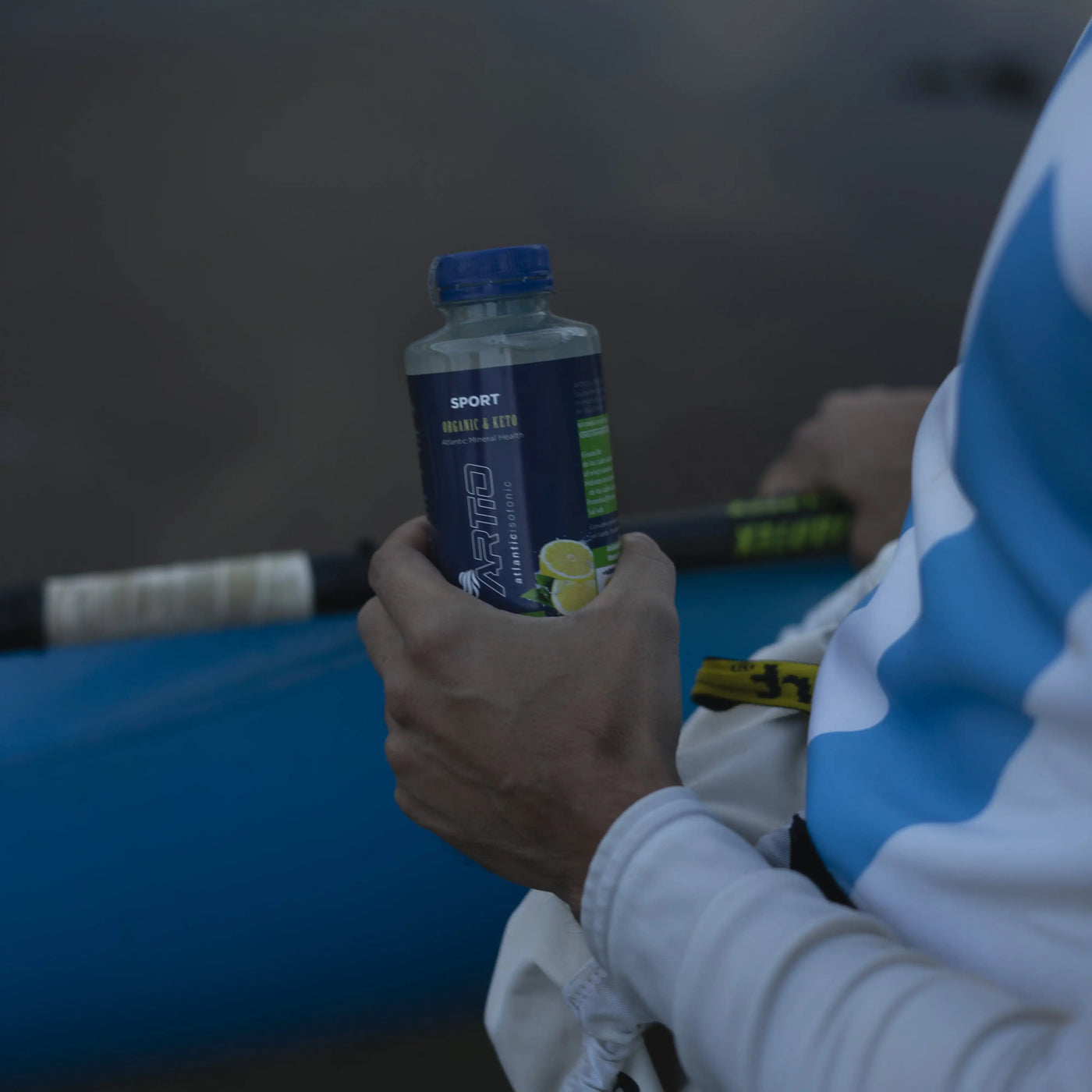 Person holding Artio sport isotonic drink lemon flavor during outdoor activity.