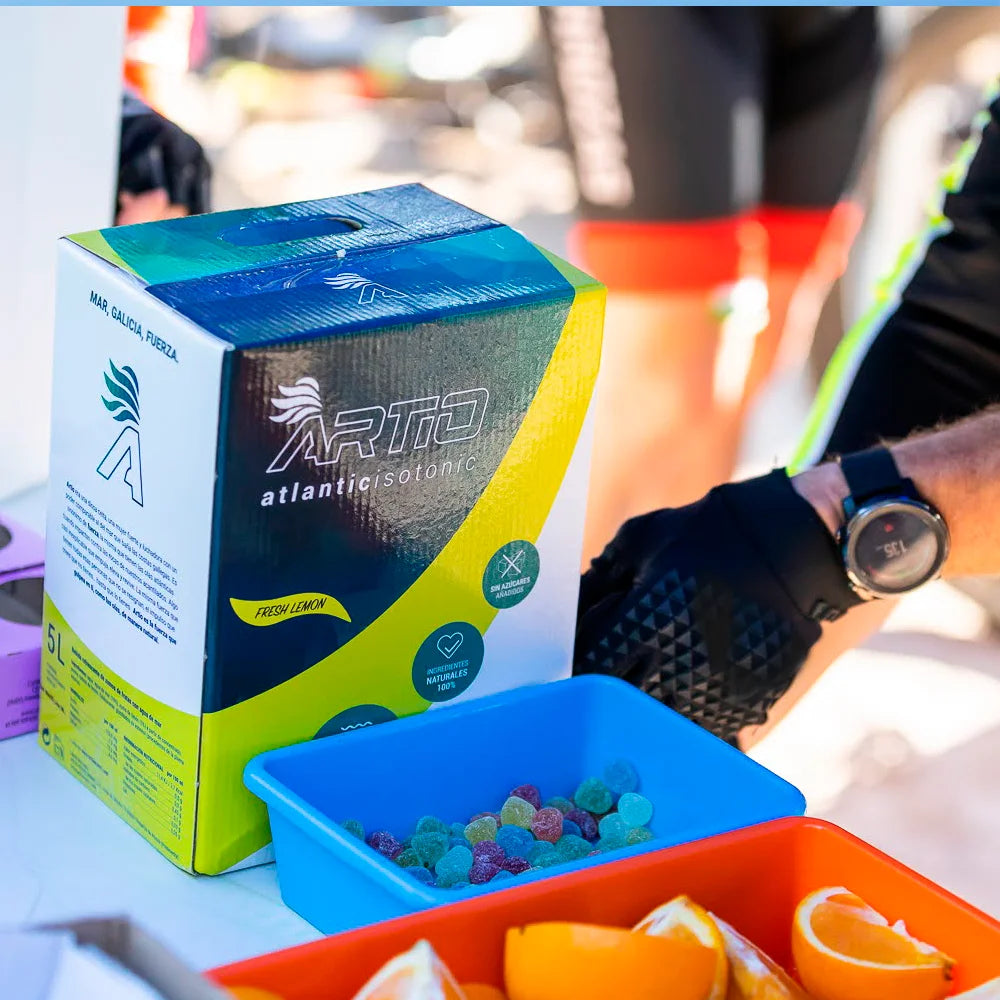 Artio sport isotonic drink in 5L box next to colorful snacks and fruit, ideal for natural hydration and optimal performance.