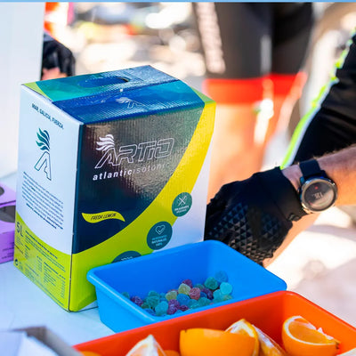 Artio sport isotonic drink in 5L box next to colorful snacks and fruit, ideal for natural hydration and optimal performance.