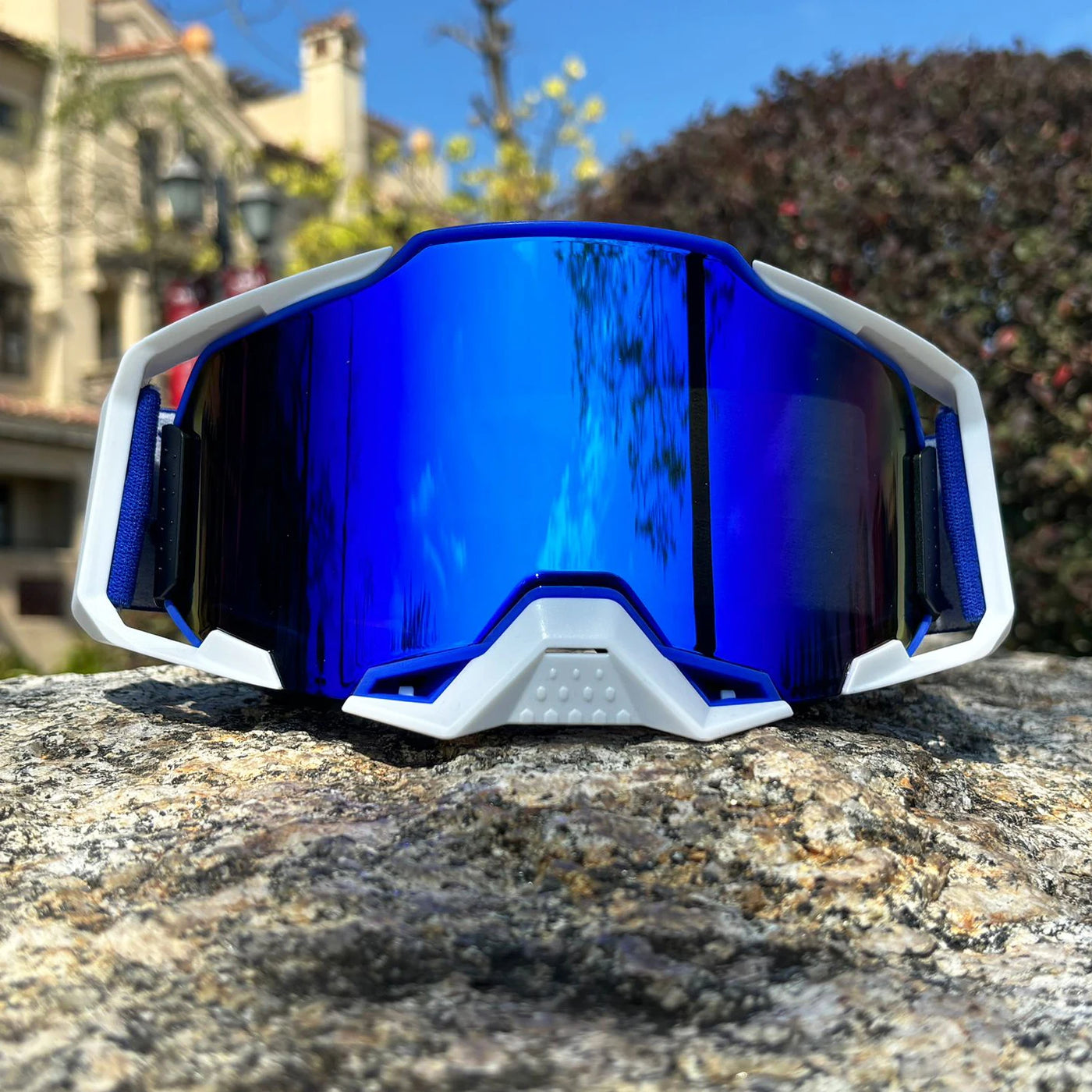Front view of blue lens motorcycle goggles on a rock, ideal for off-road MTB and dirt bike racing.