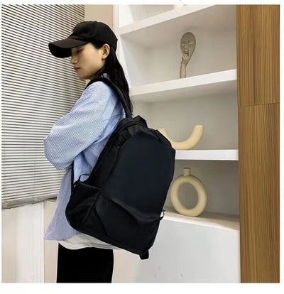 Side view of a woman wearing a black unisex backpack, showcasing its stylish design and practical use for students.
