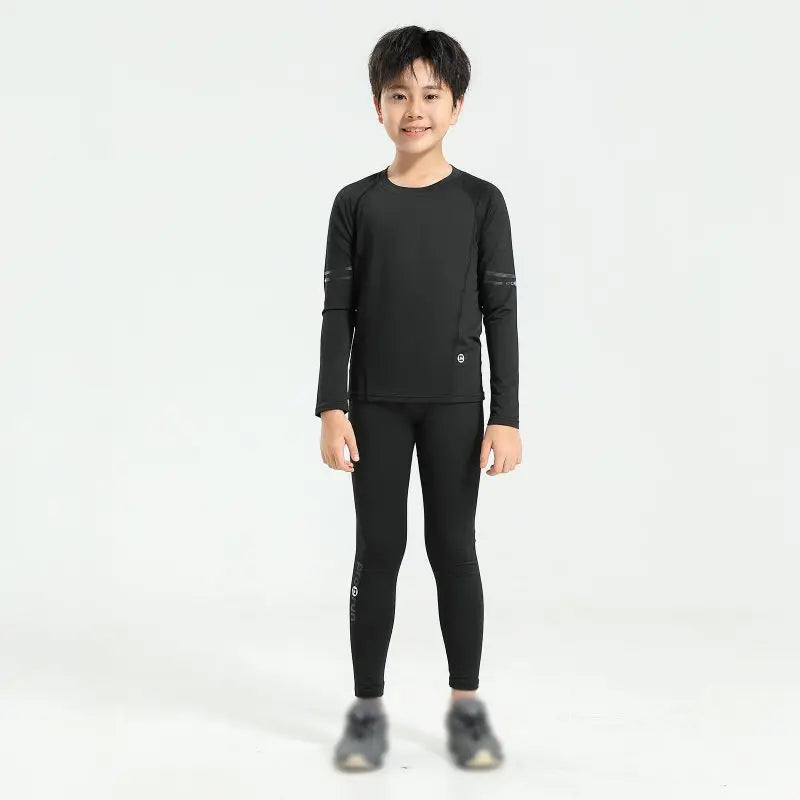 Boy wearing black thermal compression sportswear set, ideal for basketball and soccer, featuring quick-dry polyester material.