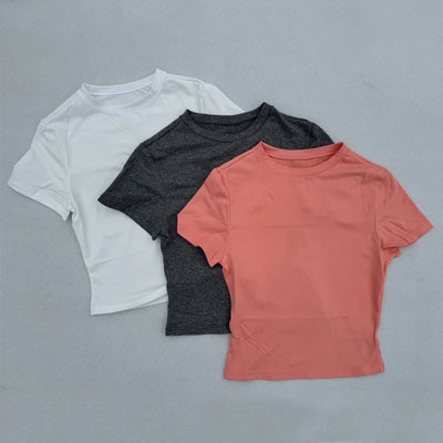 Three women's short sleeved sports t-shirts in white, black, and coral, made from breathable quick-drying fabric.