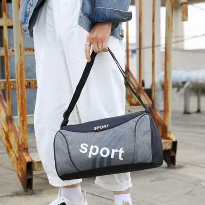 Grey gym bag with sport branding held by a person in casual attire, ideal for men and women fitness training.