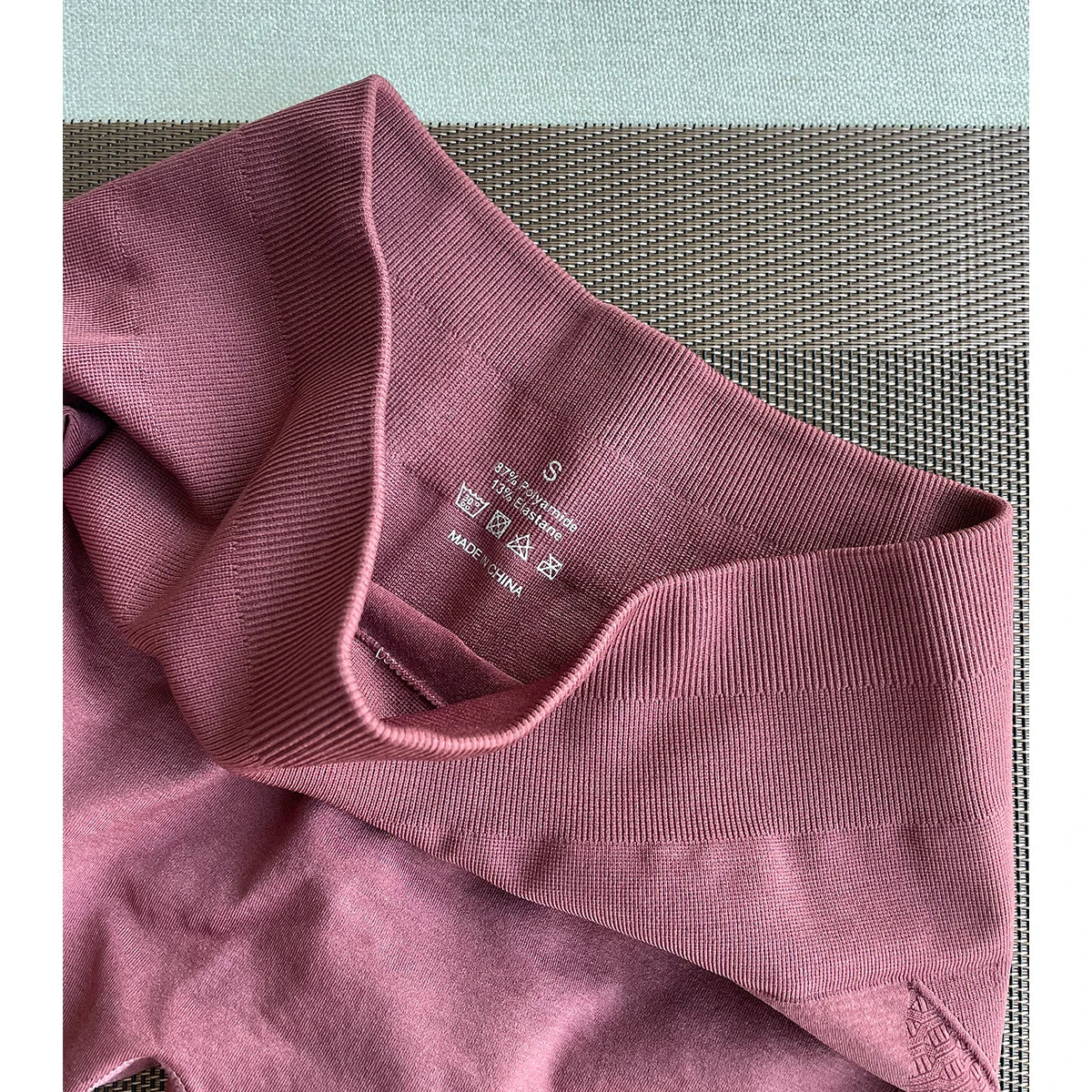 Close-up of the waistband and label of women’s Amplify Contour Shorts in a soft maroon, made from nylon and spandex.