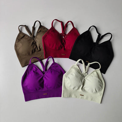 Colorful seamless women's yoga bras in various shades including brown, burgundy, black, purple, and white.