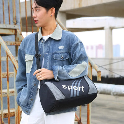 Man carrying a stylish black and gray gym bag with 'sport' branding, wearing a denim jacket, perfect for fitness and travel.