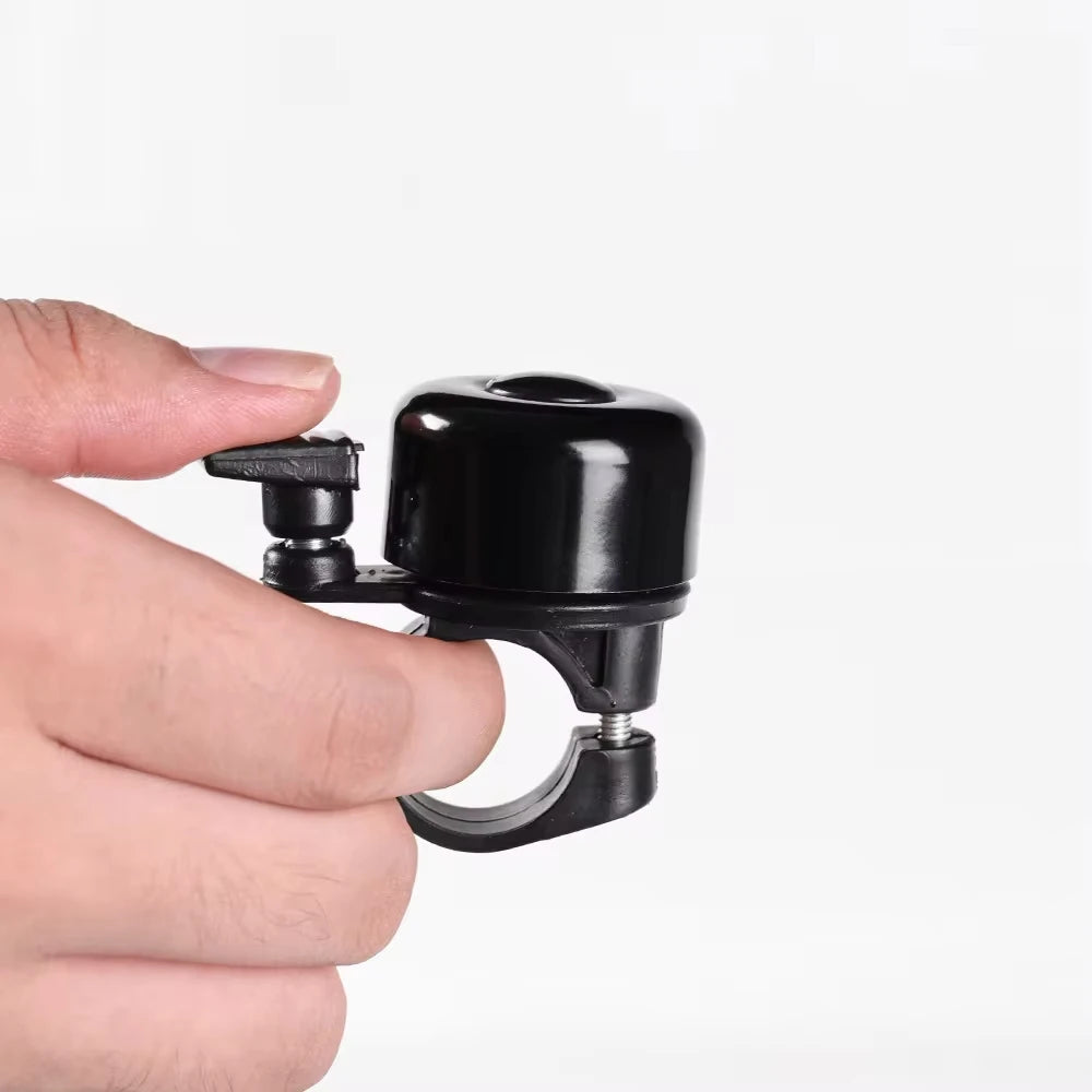 Hand holding a black aluminum alloy MTB bicycle bell, showcasing the loud handlebar safety horn design.
