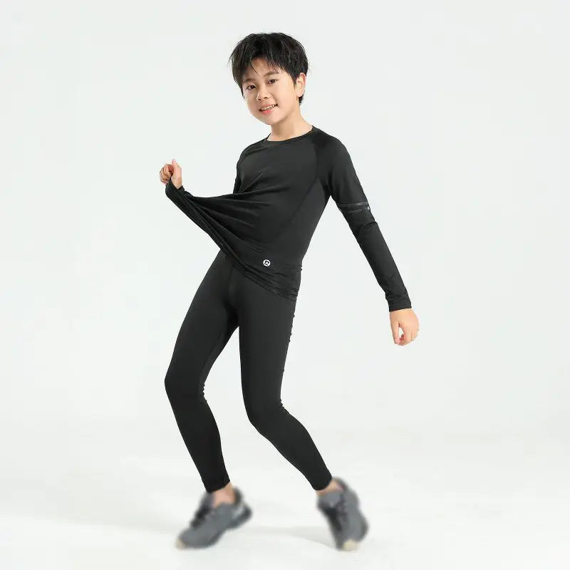 Boy wearing black thermal compression sportswear, ideal for basketball and soccer activities, showcasing flexibility and comfort.