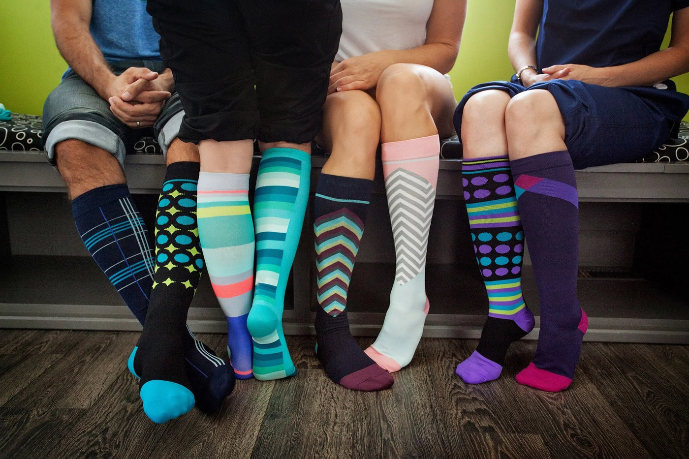 Group of people wearing colorful knee-high compression socks in various patterns and styles.