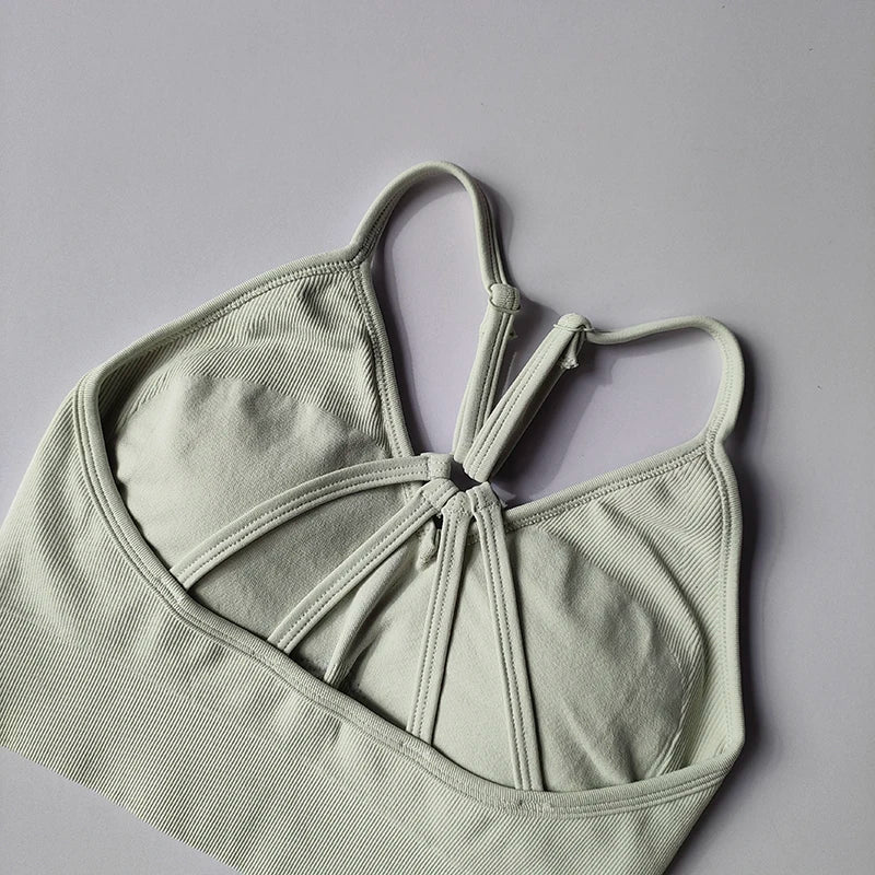 Seamless women's yoga bra in light green with unique design, perfect for fitness and toning activities.