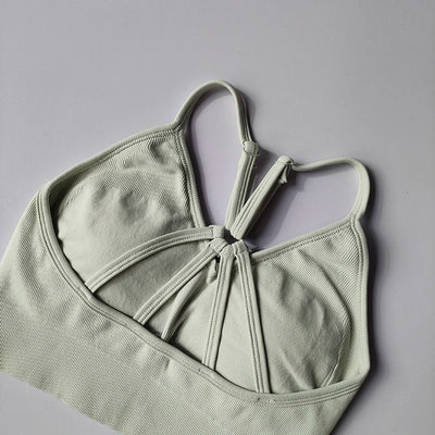 Seamless women's yoga bra in light green with unique design, perfect for fitness and toning activities.