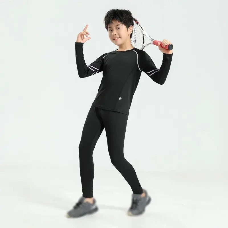 Young boy wearing boys' thermal compression sportswear set for basketball and soccer, with a tennis racket.