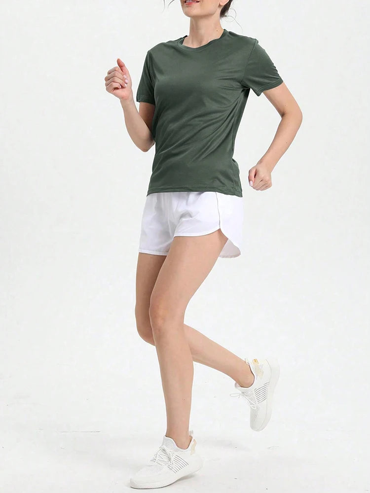 Woman running in a lightweight green ultralight quick-dry sport T-shirt and white shorts, perfect for gym or outdoor activities.