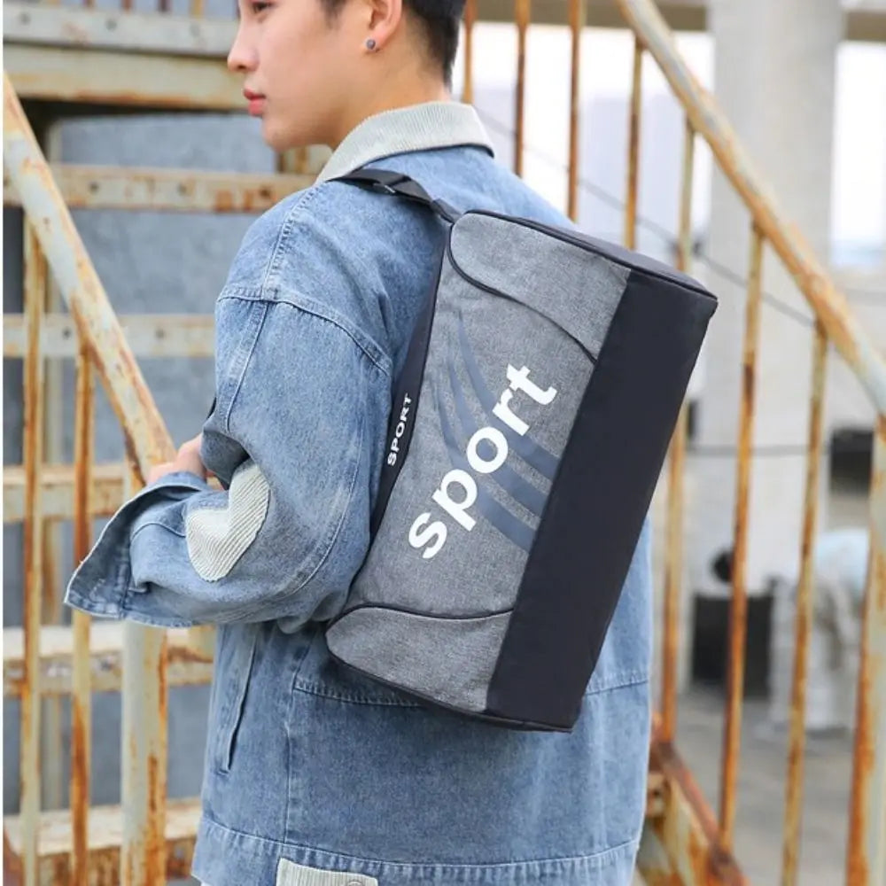 Grey gym bag with 'sport' text, worn on shoulder by a person in denim jacket, suitable for fitness and travel.