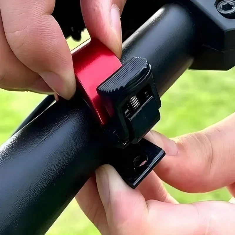 Hands installing a red bike bell on a black handlebar for cycling safety with Soud Use MTB horn.