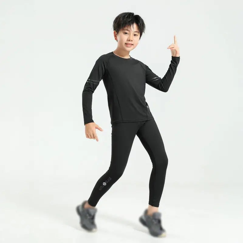 Young boy in black thermal compression sportswear set for basketball and soccer, showcasing flexibility and comfort.