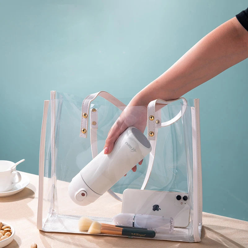 Hand holding GIANXI insulated stainless steel water bottle in a clear tote bag on a table.
