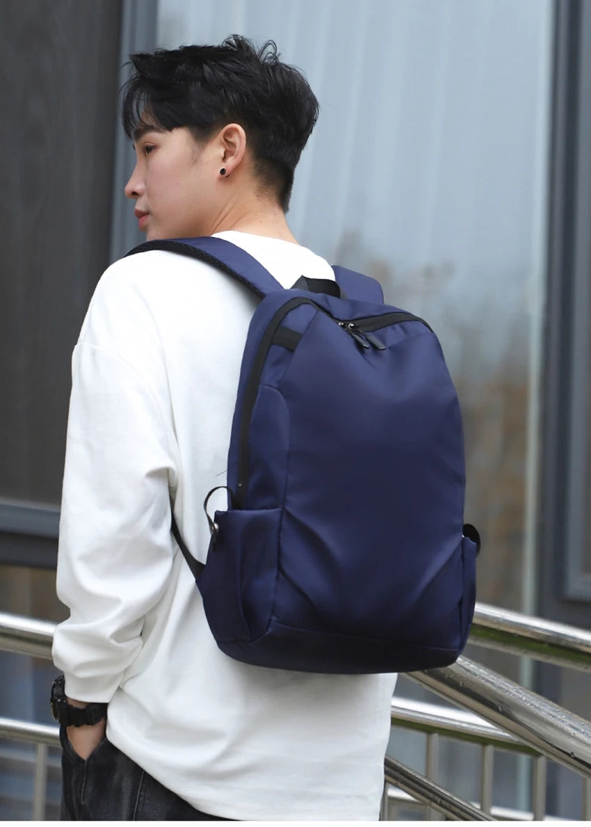 Unisex navy backpack being worn by a young man, showcasing soft straps and a fashionable design.