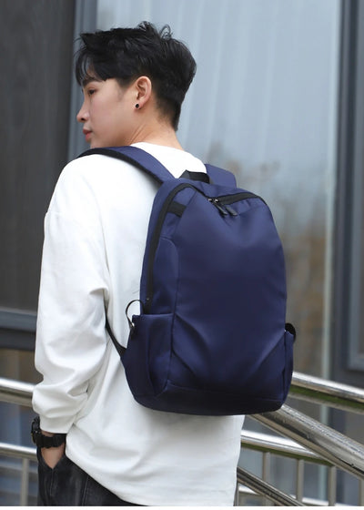Unisex navy backpack being worn by a young man, showcasing soft straps and a fashionable design.