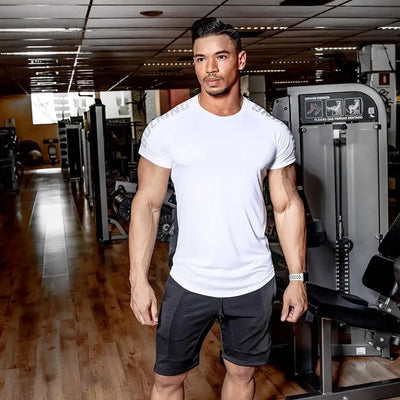 Man in a white quick-dry running T-shirt and shorts at the gym, showcasing fitness apparel for summer workouts.