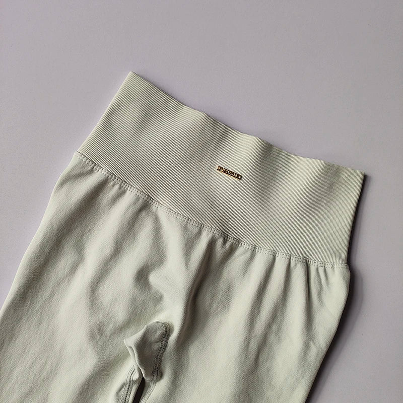 Close-up of seamless high-waisted yoga leggings featuring a ribbed waistband and logo for women's fitness wear.