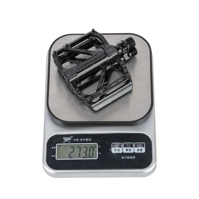 Lightweight non-slip cycling pedals on a digital scale showing 273 grams, designed for BMX and road bicycles.