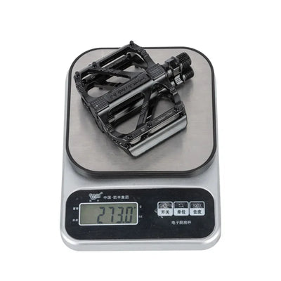 Lightweight non-slip cycling pedals on a digital scale showing 273 grams, designed for BMX and road bicycles.