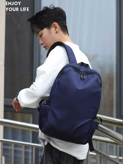 Young man wearing a navy blue backpack, showcasing a stylish and functional design perfect for students and everyday use.