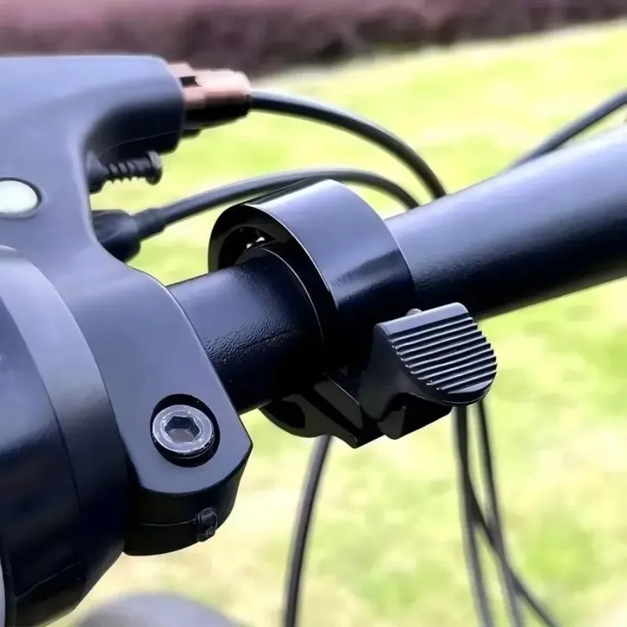 Close-up of a black bike bell mounted on a handlebar for safety in cycling and MTB rides.