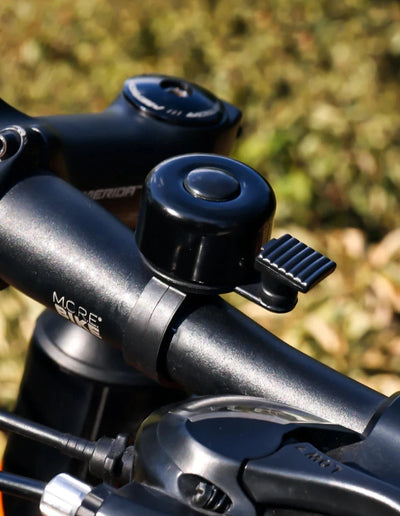 Aluminum alloy MTB bicycle bell on handlebar, designed for safety with a loud horn for alerting pedestrians.