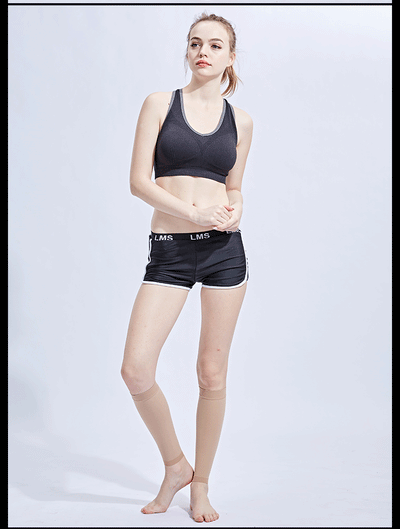 Model wearing a black sports bra and shorts, displaying compression calf socks for varicose veins and edema support.