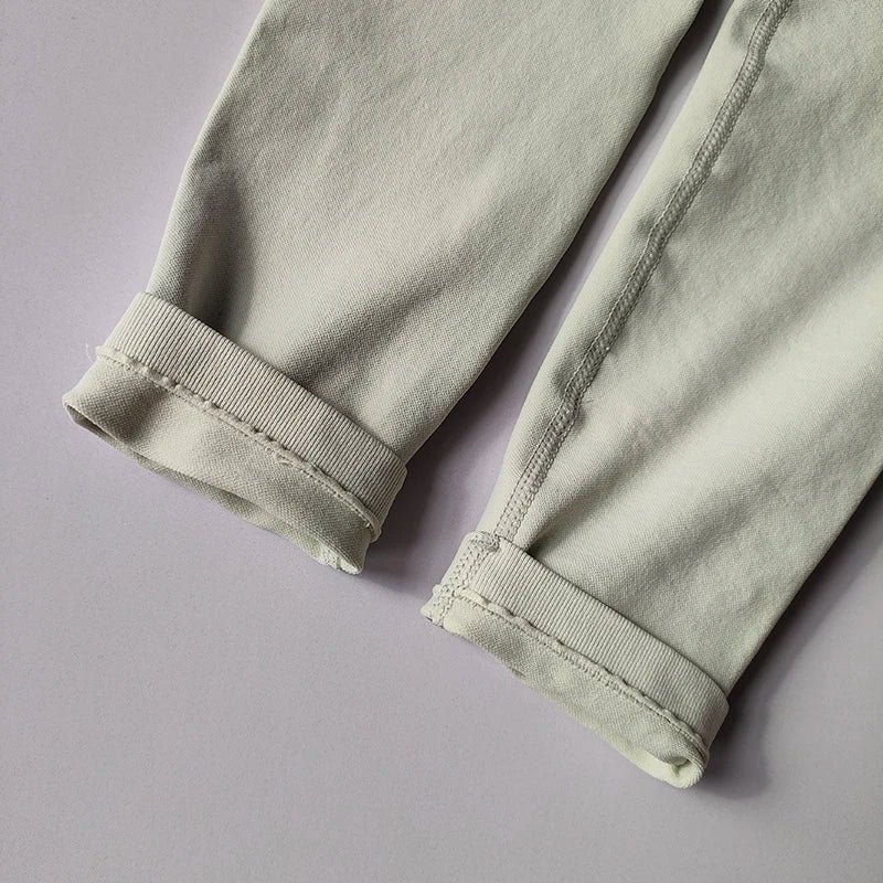 Close-up of the cuffs on seamless women's yoga leggings in light grey fabric, highlighting knit texture and design.