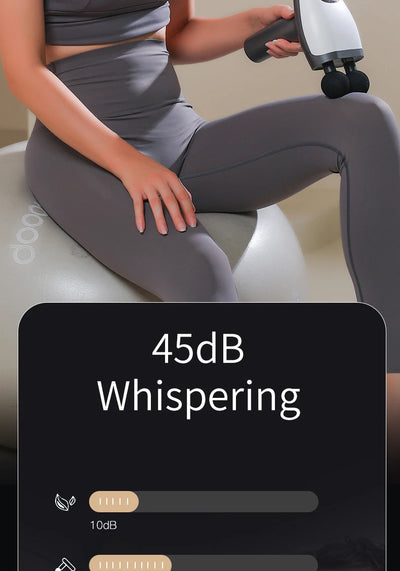 A woman using a quiet 45dB double-headed massage gun for deep tissue relief while seated on a stability ball.