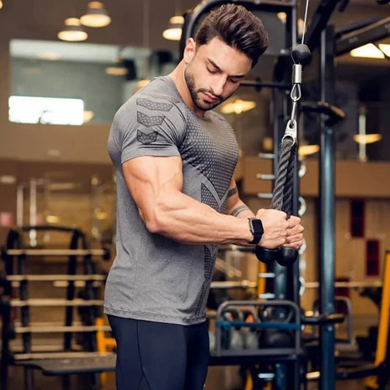 Man exercising in a grey 2024 men’s quick dry running sports T-shirt, showcasing a muscular build in a gym setting.