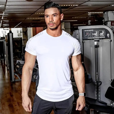 Man in a white quick-dry training t-shirt at the gym, showcasing fitness apparel for bodybuilding and activewear.