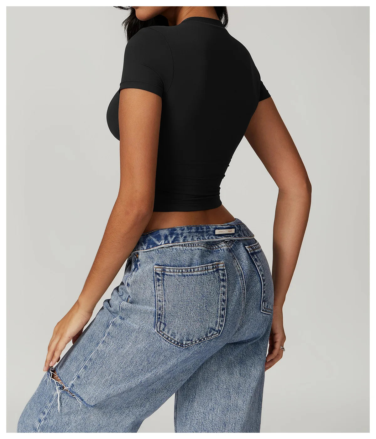 Women's tight fitting black sports t-shirt paired with stylish blue jeans, showcasing a sleek and modern outfit.