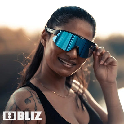 Model wearing BLIZ Breeze polarized sunglasses with blue lenses, showcasing UV protection for cycling and outdoor sports.