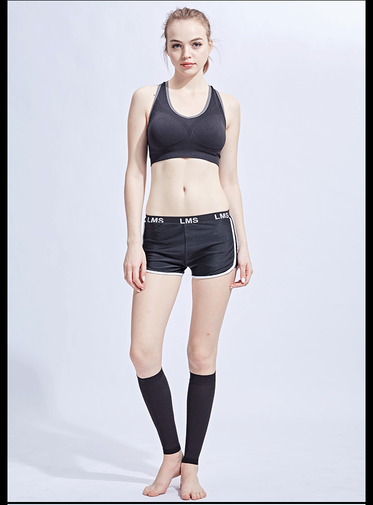 Model wearing a black sports bra, shorts, and compression calf sleeves, showcasing athletic wear for fitness or sports activities.