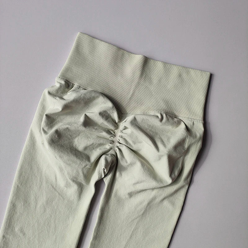 Seamless light green women's yoga leggings with a high waistband and ruched detailing for fitness and toning.