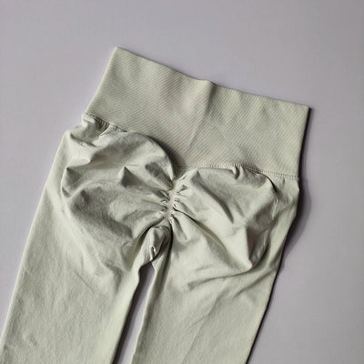 Seamless light green women's yoga leggings with a high waistband and ruched detailing for fitness and toning.